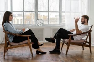 A therapist engaging in a counseling session with a male patient to support mental health.